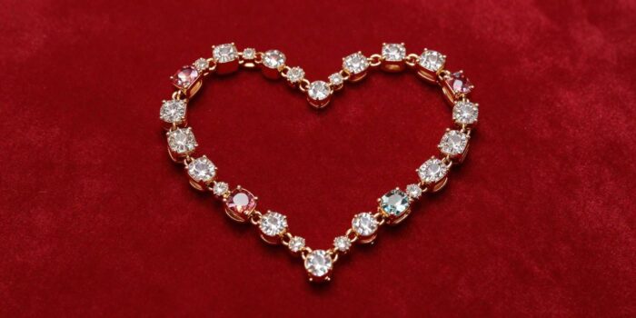 Valentine’s Day jewelry quotes image featuring elegant jewelry arranged in a heart shape.